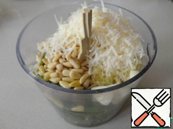 Put the washed and dried basil, pine nuts, 3 tablespoons of grated parmesan, garlic and 1/3 olive oil in the blender bowl. Whisk the sauce well.
