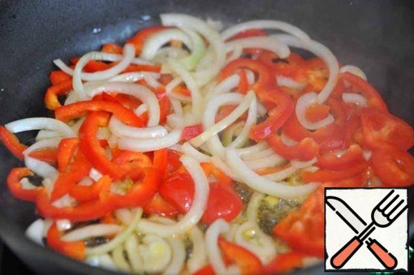 For cooking, it is better to take a wok. In the absence, use a frying pan (saucepan) with a thick bottom.
Fry the onion and bell pepper in vegetable oil for 2 minutes.