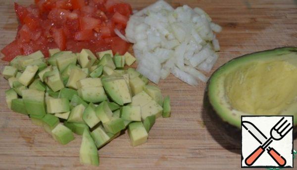 Ripe avocado cut into two halves, clean one half and remove the bone.
Peeled avocado, onions and tomatoes cut into cubes. The other halves to take out a little flesh (with a spoon) and prisolit, not cleaned.