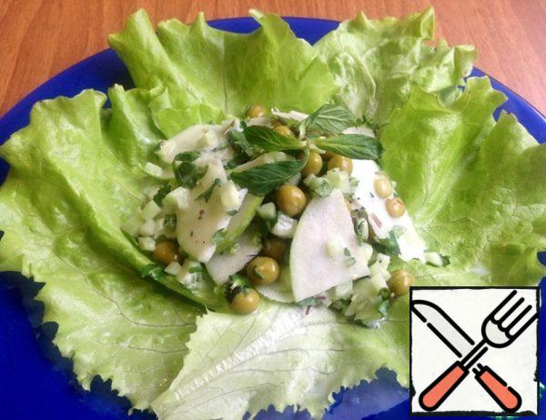 Lettuce put on a plate and then the salad itself, already seasoned with sauce and mixed.