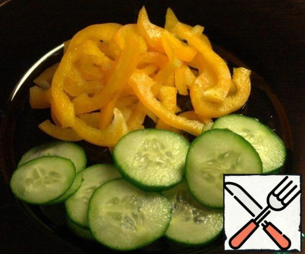Cut cucumber into slices, pepper into strips.
