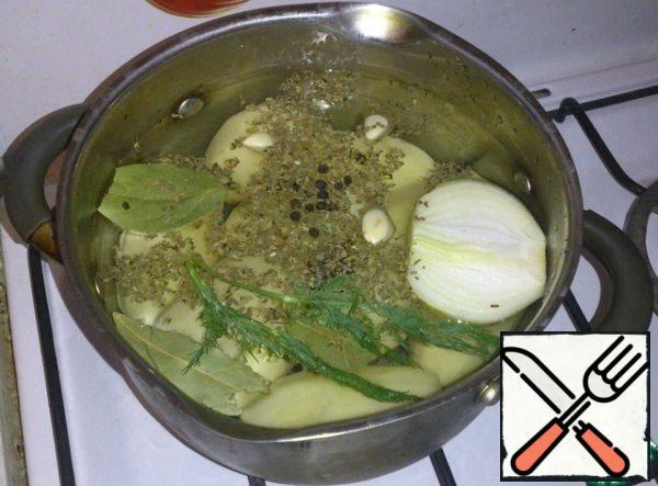Put the potatoes to cook. Fill the potatoes with cold water. Toss the bay leaf, pepper, 2 cloves of garlic, half an onion, basil and dill into the water. Put on the fire and cook until tender. Add salt ten minutes before cooking.
