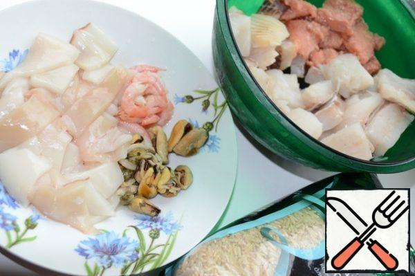 Fillet of pink salmon, cod, tilapia cut into large pieces. Shrimp clean. The squid is cleaned and cut into pieces.