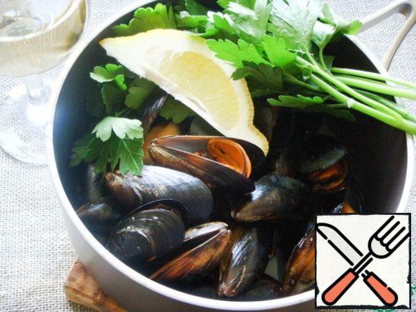Now you can start cooking paella. Traditionally, paella is cooked over an open fire, and in this case, because of the high temperature, cold water is used. In the home version, it is worth using hot liquid and it makes sense to cook broth. The broth can be vegetable/meat or fish (for example, on shrimp shells).
I had mussels in shells in a/c (alas, I didn't find any others). So I decided to use the juice from mussels as a base for the broth. I poured the thawed mussels into a saucepan and warmed them for about 1 minute with wine, parsley and a slice of lemon. If you have fresh mussels, heat them over high heat until they open. Unopened mussels should be thrown away.