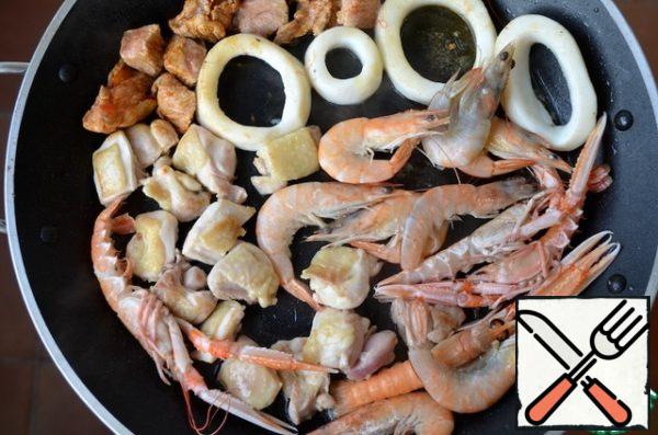 In a frying pan, heat the olive oil and fry the pieces of meat, shrimp and cuttlefish for 2 minutes on each side and put on a plate.
