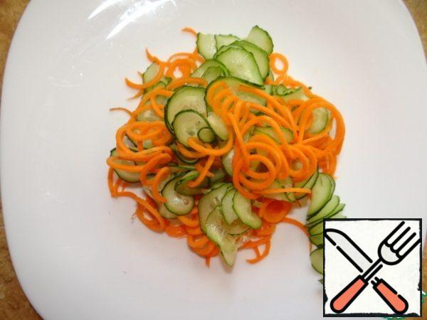 Carrots and cucumber cut into a thin spiral or thin straw, put on a plate, mix.