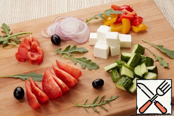 Coarsely chop all the vegetables and put them on a plate.
Cut the feta cheese into large cubes and place it around the vegetables.