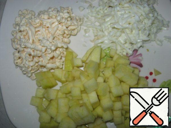 And so we will prepare our products. The whites of the eggs to RUB on a large grater, and the yolks will go to the top layer. Also grate the processed cheese on a coarse grater. Apple peel and cut into small cubes.