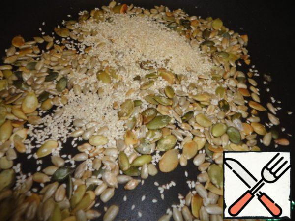 Fry the pumpkin and sunflower seeds in a dry frying pan until golden brown. Add sesame seeds and fry for 1-2 minutes. Remove from heat and pour into a bowl.
