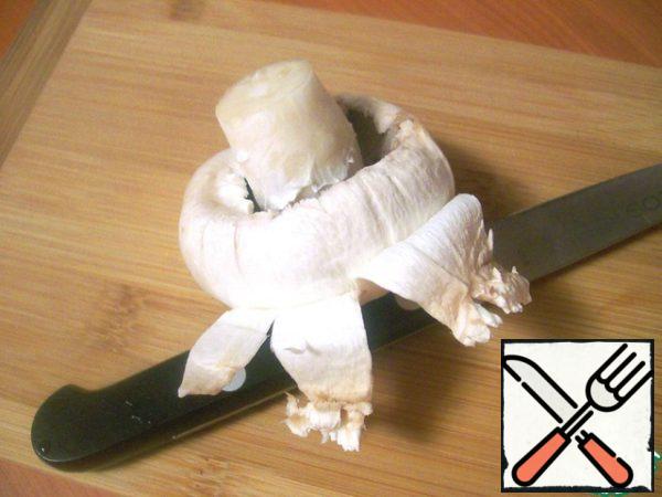 Wash the mushrooms, separate the legs (they are not needed), remove the thin white skin from the caps with a knife.
