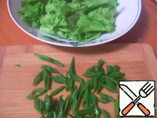 The greens of the lettuce leaves are broken into rather large pieces. Chop the onion with feathers, chop the dill very finely.
