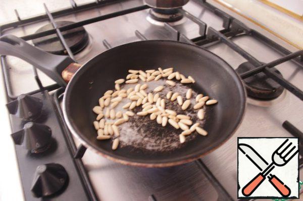 Lightly fry pine nuts in a hot frying pan.
