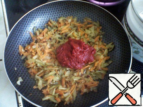 In a separate frying pan, fry the onion in vegetable oil until golden brown, add the carrots, and put out. Add cucumbers and tomato paste.
