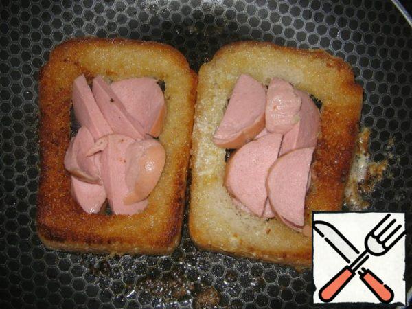 When one side is browned, turn over and put the sliced sausage in the panes.
