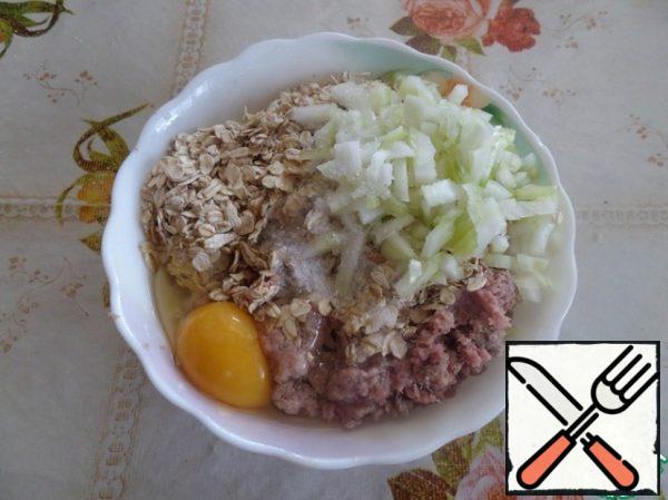 In a cup with minced meat, add oatmeal, egg, 2-3 tablespoons of finely chopped onion and salt.
