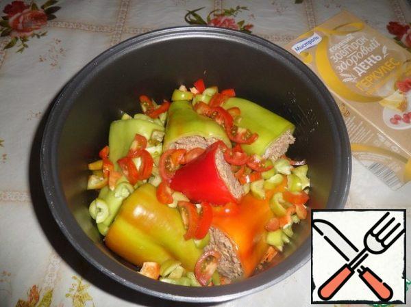 Put the stuffed peppers on top of the vegetables. Add the chopped pepper and tomato.

