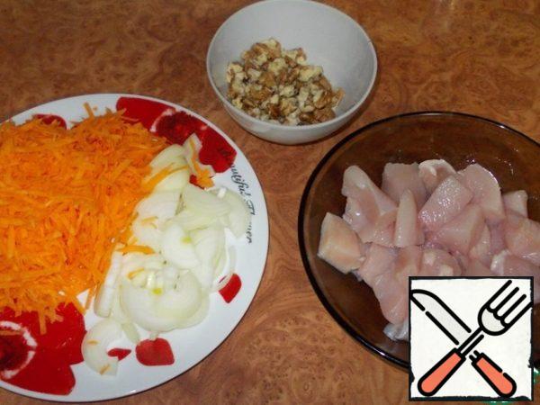 Cut the onion into half rings, grate the carrots on a coarse grater, cut the fillets into arbitrary pieces, chop the nuts not very finely.
