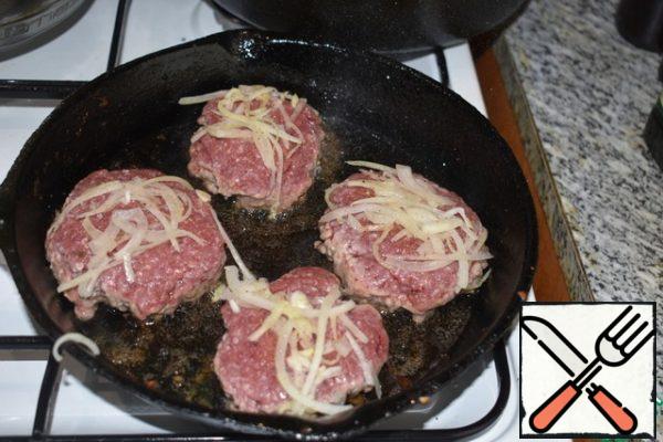 Spread the cutlets on a hot frying pan, greased with vegetable oil, with the mustard side down. Sprinkle salt and pepper on the other side and spread it with a long salted onion. Just crush it. Fry for about 5 minutes (on one side) on a sufficiently high heat until crisp.