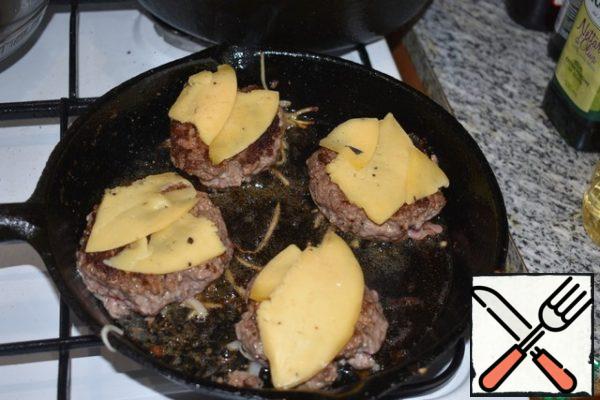 Top of the cutlets spread slices of cheese. 