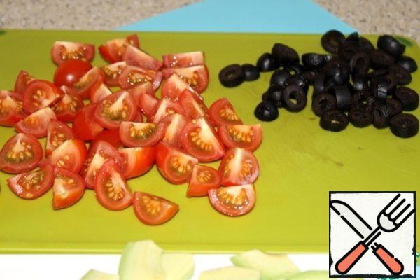Cut tomatoes into quarters, olives into rings.

