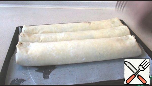 We wrap everything in a roll, with the side that is wider, it is not necessary to turn the edges, I twisted it because it did not fit on the baking sheet. The baking tray should be covered with parchment paper and greased. Similarly, wrap two strudels.
