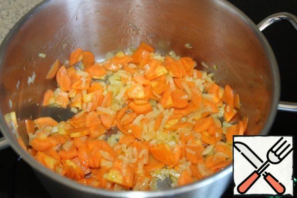 In a saucepan with a thick bottom, where the soup will be cooked later, fry the onion and carrot in olive oil until soft, about 5 minutes, until the onion turns golden.
