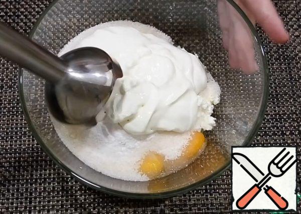 Mix in a bowl of cottage cheese, eggs, sugar, baking powder, vanilla sugar and sour cream. With the help of a submersible blender to turn everything into a homogeneous mass.
