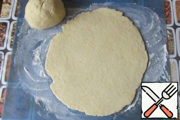 Sprinkle the work surface with flour, spread the dough and roll out to a thickness of no more than 3-4 mm. For convenience, you can roll out pieces of dough.

