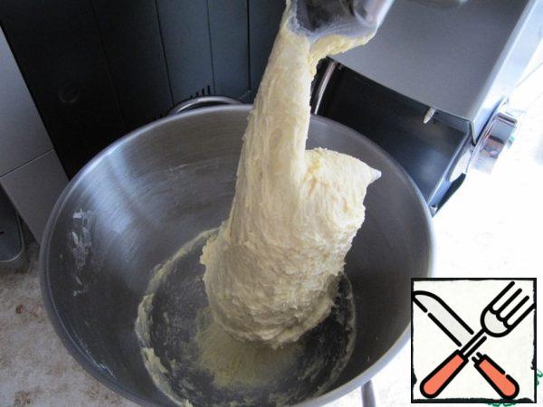 Pour the sponge cake, egg yolks whipped with sugar into a bowl, add melted warm butter, pour in warm cream, alcohol – mix with a mixer, add sifted wheat flour, salt, vanilla sugar in portions, knead the dough with a hook or a bread maker attachment. Knead the dough for 10-15 minutes. With manual kneading, first knead with a spoon, then adding flour to proceed to manual kneading. The dough turns out sticky - if you knead it by hand, you can't do without a scraper! Sprinkle the dough with flour when kneading, so that it does not clog!

