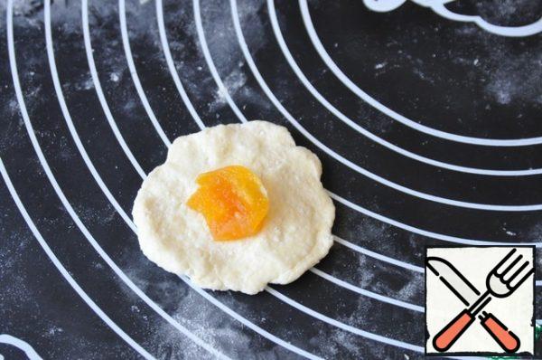 You can use two ways to form cookies. A simple way: tear off pieces of dough, roll a ball the size of a walnut, make a cake, put half a teaspoon of dried apricots in the middle.
