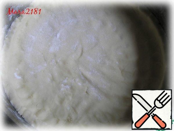 It is necessary to prepare a detachable mold (I have 25 cm in diameter), smearing it with a small amount of vegetable oil and sprinkling with flour. The structure of the dough based on rice flour is very similar to the shortbread. We shift it into a mold and manually distribute it evenly along the base, along the edge, so that a small side is formed. The thickness of the dough is approximately 1-1.5 cm.
