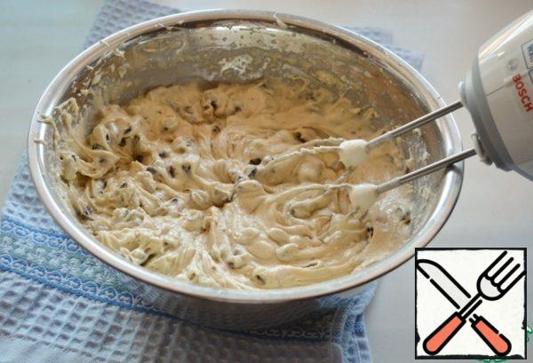 At a low speed of the mixer, add brandy with raisins and flour mixed with baking powder to the dough. The dough turns out to be quite thick, like for a cupcake.
