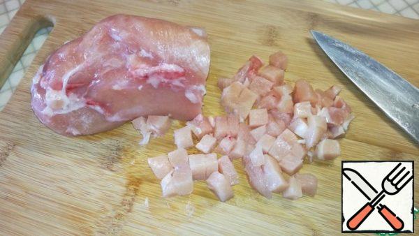While the dough is in the refrigerator, cut the chicken into small cubes. Put it in a bowl, sprinkle with salt and pepper to your liking.
