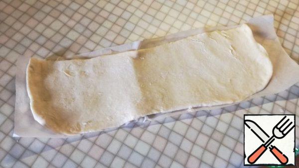 Cut out a strip of baking paper according to the height of your mold, so that it lies inside the entire wall, and roll out the dough to its full length.
