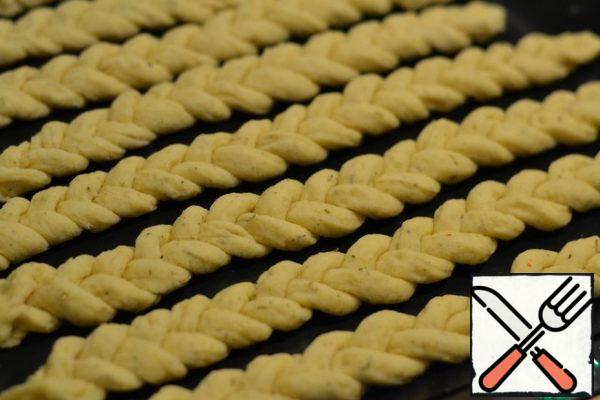 Put the finished pigtails on the prepared baking sheet, cover with a towel and leave in a warm place for 5-6 minutes.
