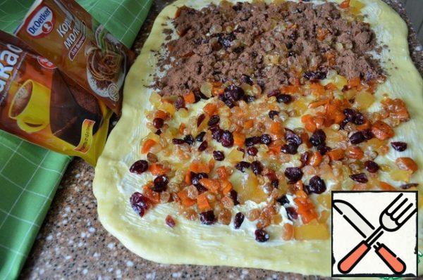 Knead the dough, roll out into a rectangular layer measuring 35 * 25 cm,
1-1.5 cm thick. Lubricate the layer with soft butter.
Put the soaked dried fruits and sprinkle with cinnamon and cocoa.
