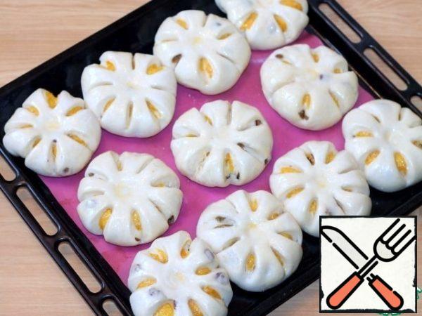 Cover the baking sheet with baking paper and grease it with vegetable oil, if the silicone mat is not greased with oil. Lay out the buns and cover with a dry towel or cling film. Place the baking tray in a warm place so that the buns increase in volume by 2 times.
