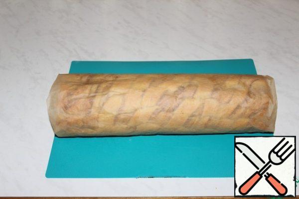 With the help of parchment, we roll it into a roll. Allow to cool completely.