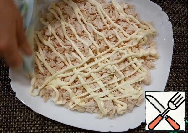 Boil the chicken fillet in salted water. Slice the chicken.
Put the first layer of chicken on a large plate, then brush with mayonnaise. I cut a corner from the mayonnaise bag and draw a grid.