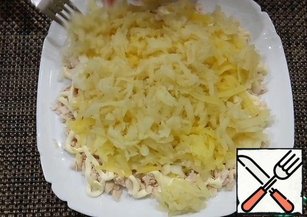 The next layer is boiled potatoes. Grate on a coarse grater, spread over the entire surface.
