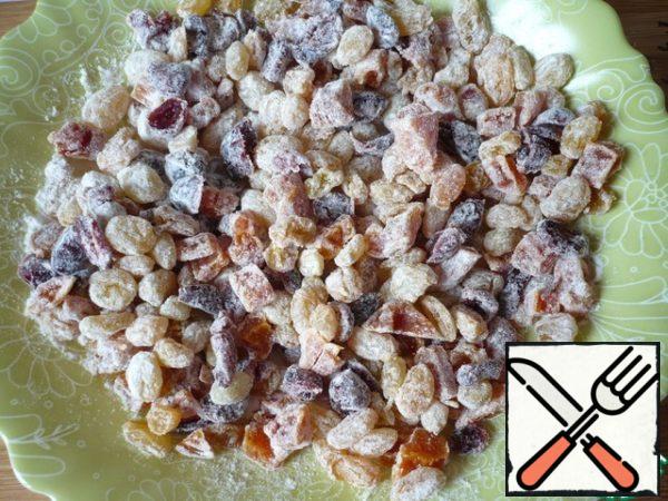 Sprinkle the dried fruits with flour and mix so that they are much better distributed in the dough.
