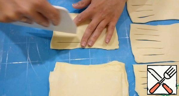 The dough is divided into 10 equal parts. Roll each part into a rectangle.
Visually, each dough is divided into two parts. On one side to make cuts.