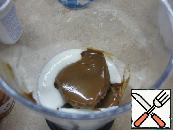 In the second part, add boiled condensed milk and half of the nuts, whisk with a blender into a homogeneous mass.
