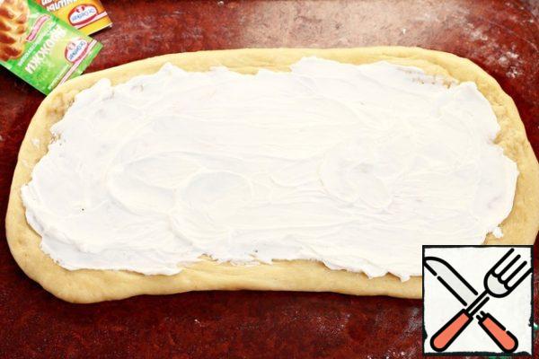Roll out the dough on a surface sprinkled with a thin layer of wheat flour (in case of stickiness) into a layer 30-40 cm long and 12-13 cm wide. Do not make the layer very thin, otherwise unwanted torn holes may appear on the surface during the delay. Without going to the edge of the formation (as in the photo), spread a uniform layer of cheese (140 g).
