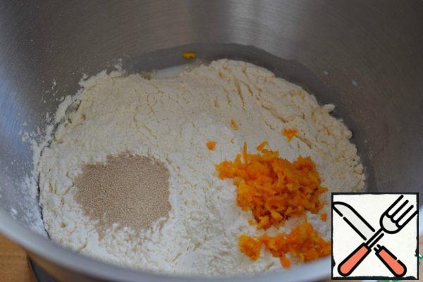 Add the sifted flour, sugar, salt, vanilla sugar, yeast and orange zest to the warm milk. There is nothing wrong with making sure that the zest is not bitter.
Since flour from different manufacturers differs in quality, then all its quantity should not be added at once. You may have to adjust the flour weight individually.
Knead a rather steep dough.
