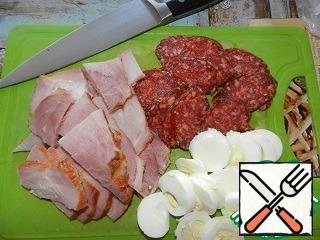 Prepare the filling. Eggs boil hard boiled, peel, cut into rings. Ham cut into thin plates, then you can take any meat products (brisket, raw pork or beef, ham, generally for every taste). Chorizo cut into rings (if other options of sausages, it is better to take spicy).