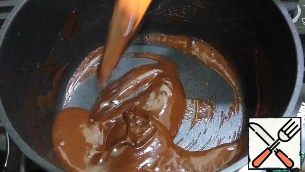 Prepare the glaze. Melt the second part of the chocolate by mixing it with milk and vegetable oil.
