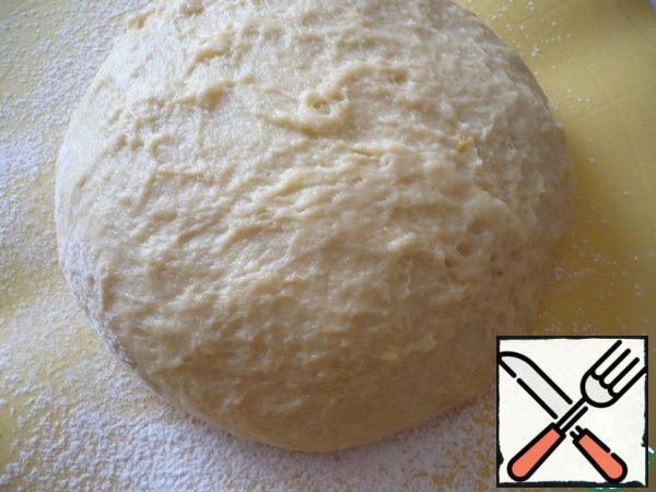 Pour 1 tablespoon of flour on the table, put a bowl with dough and start kneading.

