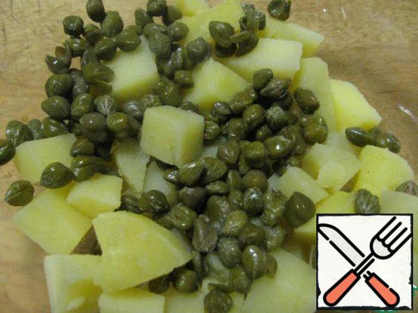 Potatoes and capers are put in a salad bowl (capers are almost impossible to find in the store, if you, like me, have problems with capers, then green olives are quite suitable).
