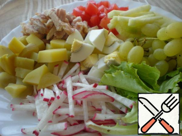 Potatoes and eggs are not cut very finely, apples and radishes are cut into strips, tomatoes are diced (without seeds and juice).
Fry the turkey meat, cool, cut into strips.
Tear the lettuce leaves with your hands, cut the grapes in half.
